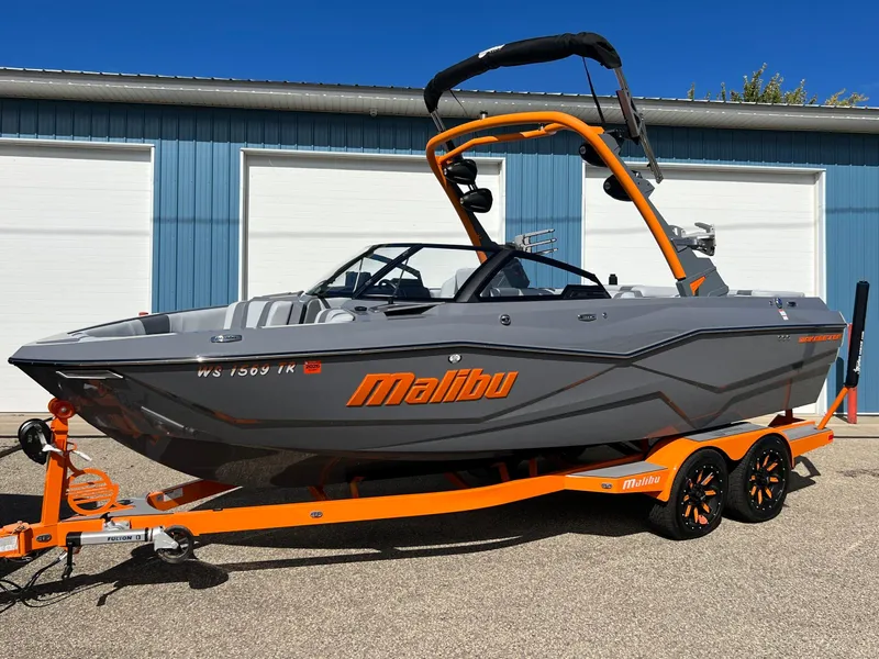 Slide: The Image of 2023 Malibu Wake Setter LSV 22 boat on orange trailer, parked outside blue garage. - 34
