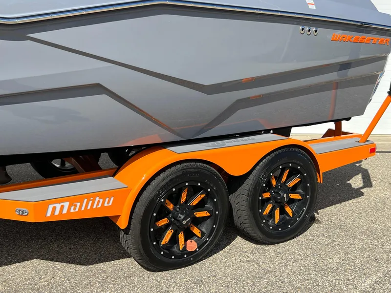 Slide: The Image of 2023 Malibu Wake Setter LSV 22 boat on orange trailer with stylish black wheels. - 35