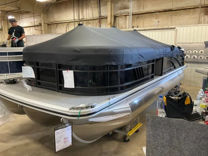Slide: The Image of 2023 Bennington 21LSB pontoon boat with black cover in a warehouse setting. - 0