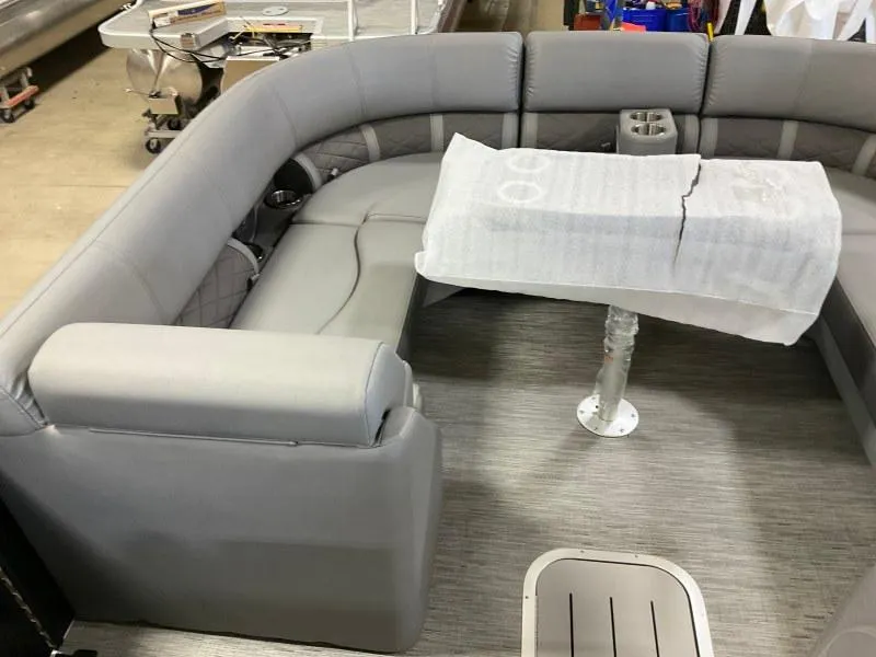 Slide: The Image of 2023 Bennington 21LSB pontoon boat interior with gray seating and covered table. - 11