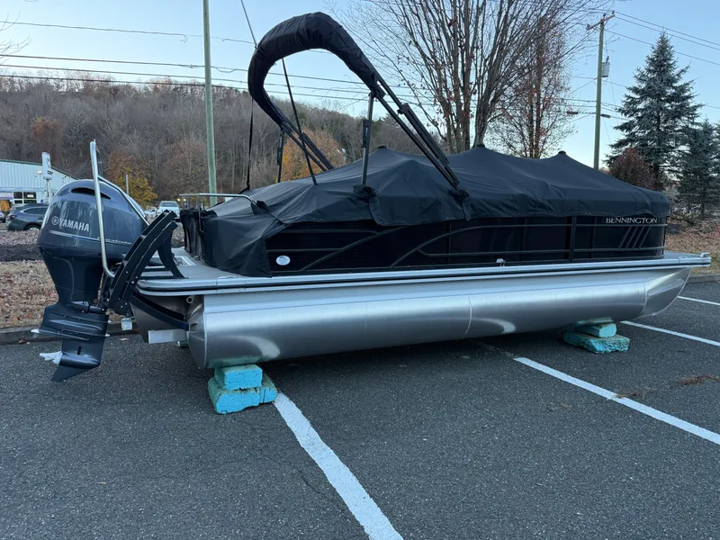 Slide: The Image of 2023 Bennington 21LSB pontoon boat with Yamaha motor, covered and parked outdoors. - 18