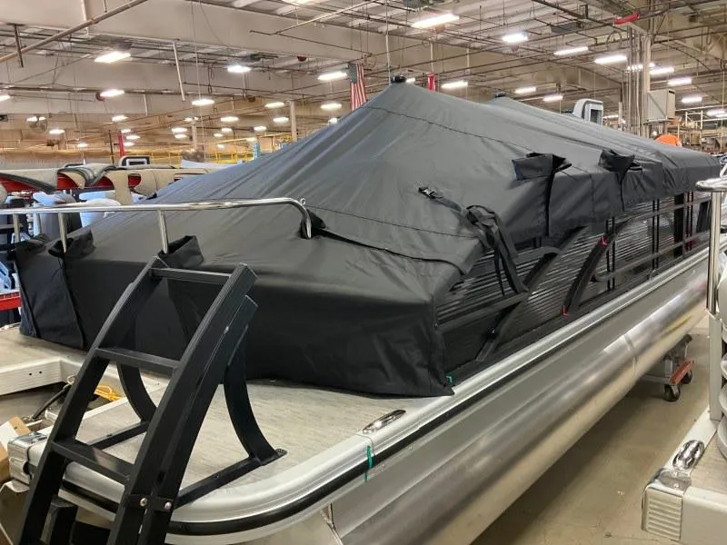 Slide: The Image of 2023 Bennington 21LSB pontoon boat covered in a black tarp indoors. - 2