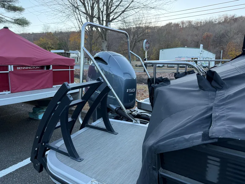 Slide: The Image of 2023 Bennington 21LSB pontoon boat with Yamaha 150 engine, docked outdoors. - 21