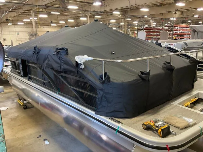 Slide: The Image of 2023 Bennington 21LSB pontoon boat covered in a protective tarp in a warehouse. - 3