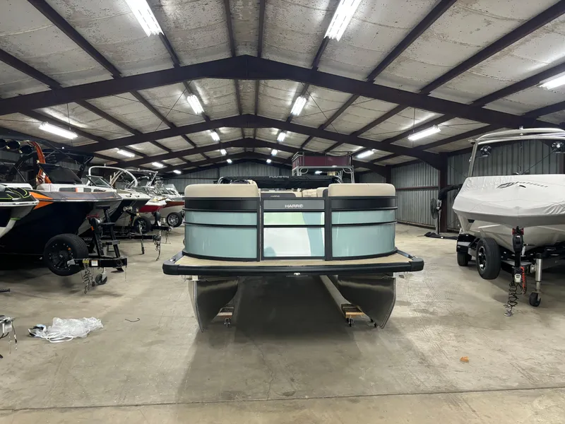 Slide: The Image of 2025 Harris Cruiser 230 pontoon boat in a spacious indoor storage facility. - 10