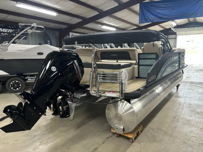 Slide: The Image of 2025 Harris Cruiser 230 pontoon boat in a showroom, featuring a powerful outboard motor. - 11