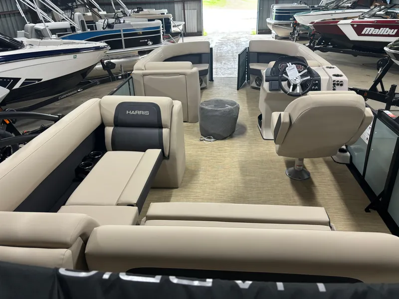 Slide: The Image of 2025 Harris Cruiser 230 pontoon boat interior with beige seating in a showroom. - 9