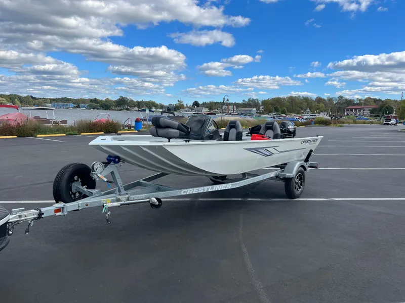 Slide: The Image of 2025 Crestliner 1600 Storm boat on trailer in parking lot, under blue sky. - 7
