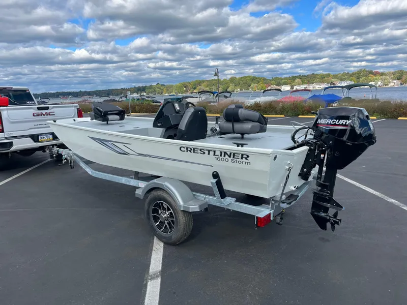 Slide: The Image of 2025 Crestliner 1600 Storm boat on trailer, parked near a lake under cloudy skies. - 8