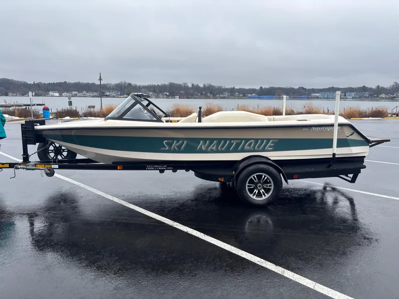 Slide: The Image of 1995 Correct Craft Ski Nautique boat on trailer in parking lot near lake. - 0