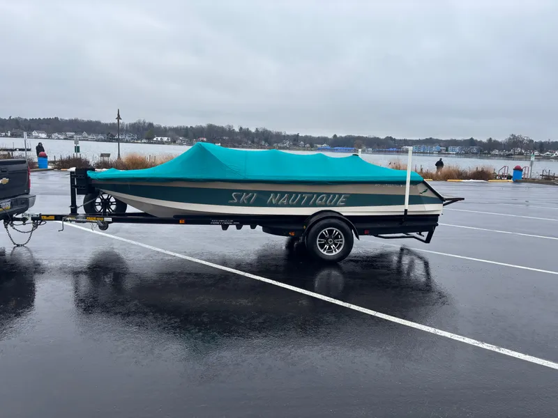 Slide: The Image of 1995 Correct Craft Ski Nautique boat on trailer with teal cover in parking lot. - 6