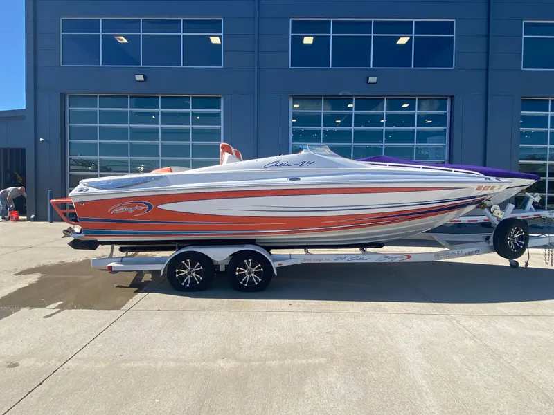 The Image of 2019 Baja 24 Outlaw speedboat with vibrant orange and purple accents on a trailer. - 0