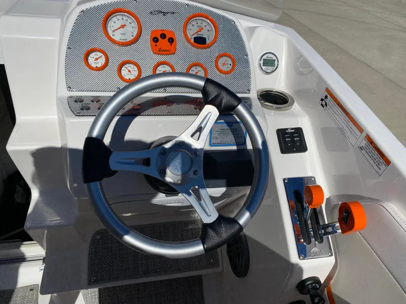 Slide: The Image of 2019 Baja 24 Outlaw boat dashboard with steering wheel and orange-accented gauges. - 14