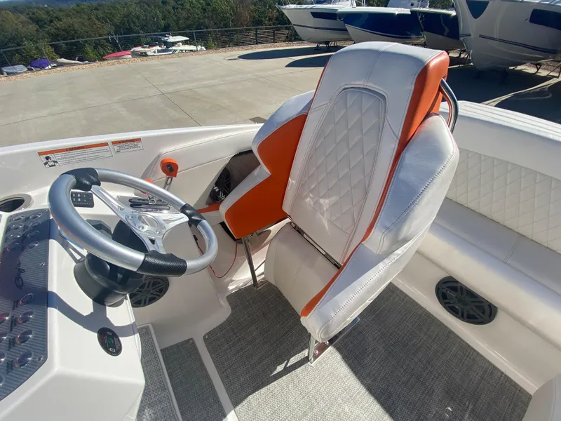 Slide: The Image of 2019 Baja 24 Outlaw boat interior with orange and white seating, steering wheel, and dashboard. - 17
