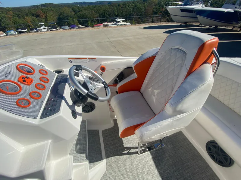 Slide: The Image of 2019 Baja 24 Outlaw boat interior with orange and white seating, steering wheel, and dashboard. - 18