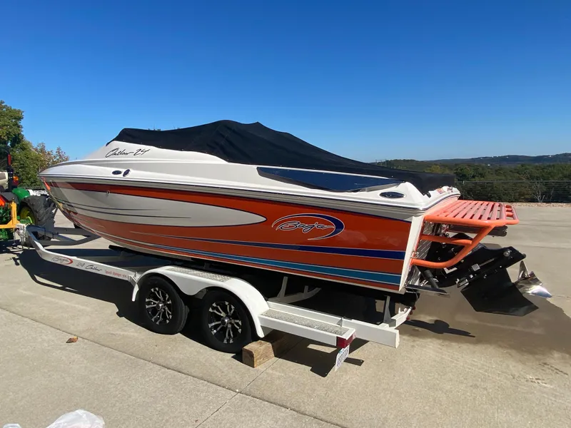 Slide: The Image of 2019 Baja 24 Outlaw boat on trailer, orange and white design, parked outdoors. - 29