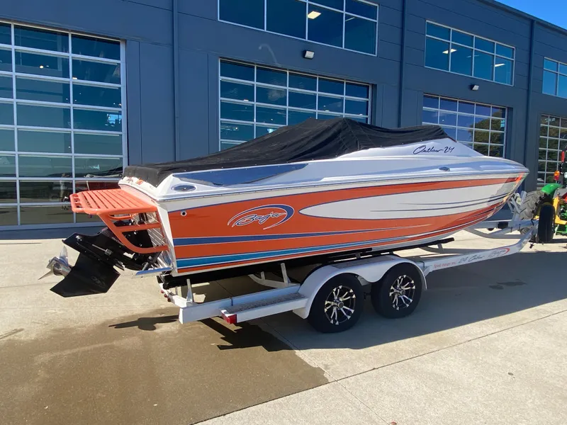 Slide: The Image of 2019 Baja 24 Outlaw speedboat on trailer, orange and white design, parked outside a building. - 30