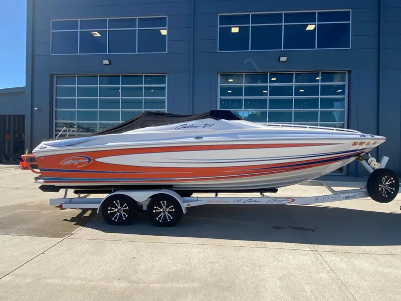 Slide: The Image of 2019 Baja 24 Outlaw boat with vibrant orange and white design on a trailer. - 31