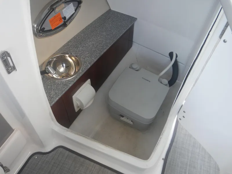 Slide: The Image of 2020 Chaparral 24 SSI boat interior with compact toilet and sink. - 8