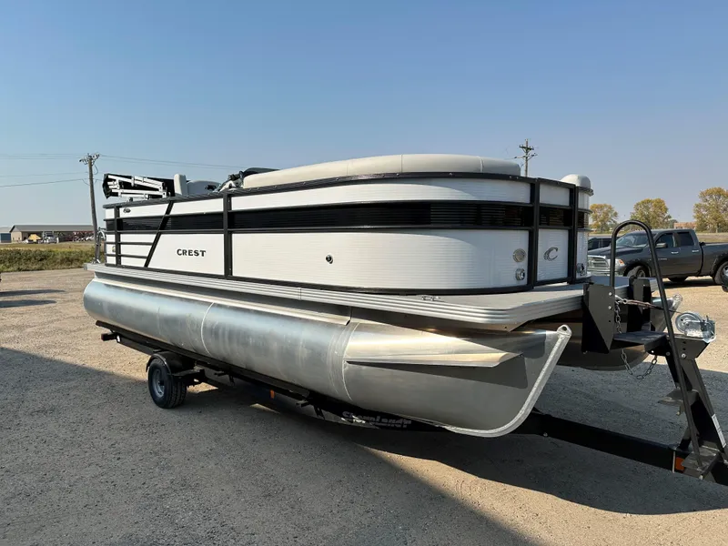 Slide: The Image of 2022 Crest Classic DLX 220 pontoon boat on trailer, parked outdoors. - 3