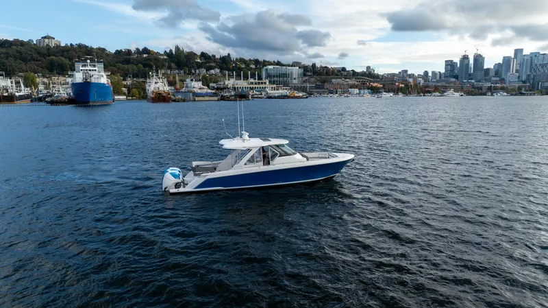 Slide: The Image of 2020 Tiara Sport 38 LS boat cruising on a scenic waterfront with city skyline. - 15