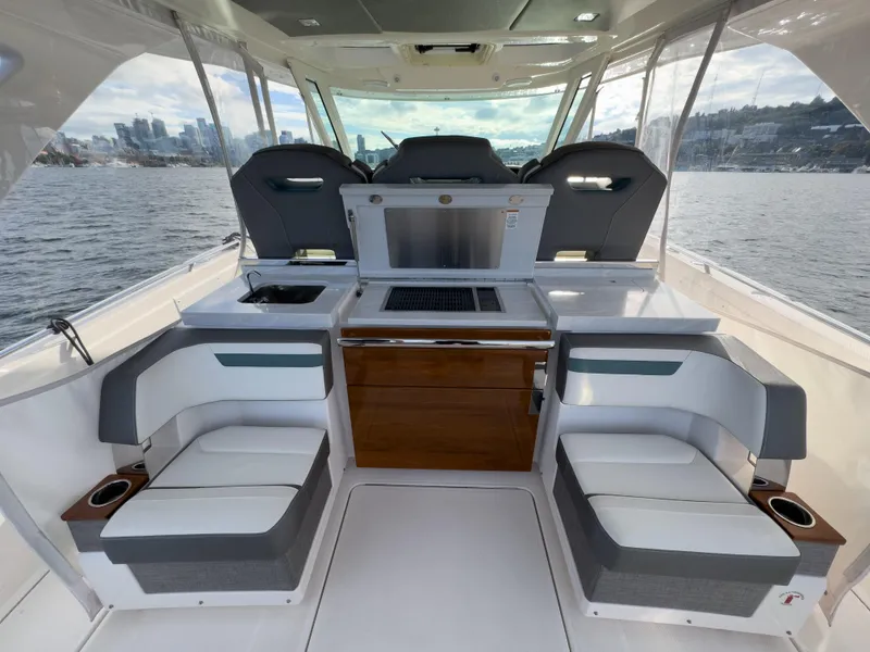 Slide: The Image of 2020 Tiara Sport 38 LS boat interior with seating and helm, on a scenic water backdrop. - 23