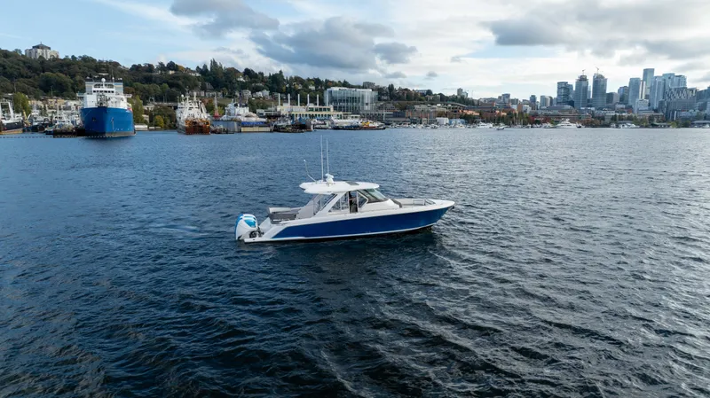 Slide: The Image of 2020 Tiara Sport 38 LS boat cruising on a scenic waterfront with city skyline. - 4