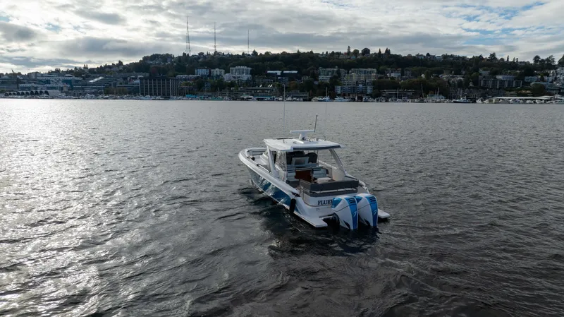 Slide: The Image of 2020 Tiara Sport 38 LS boat on a calm lake with cityscape background. - 5