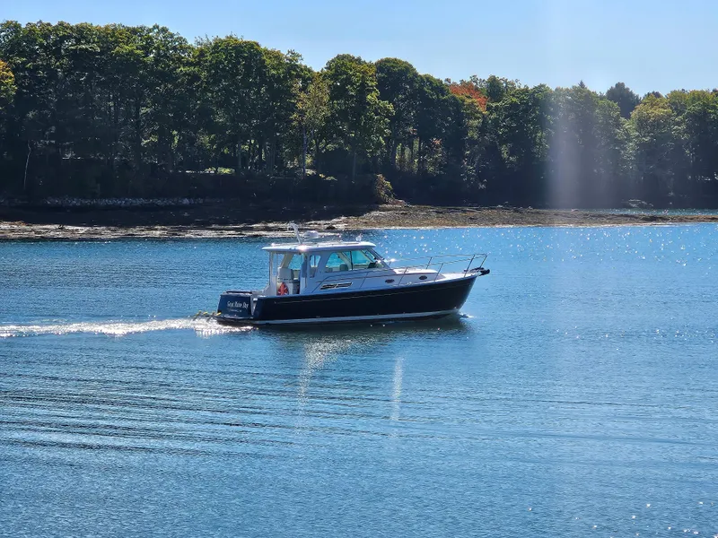 Slide: The Image of 2008 Back Cove 33 boat cruising on a serene lake with forested shoreline. - 2