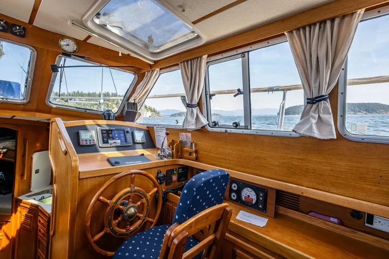 Slide: The Image of Pilot house interior of 2000 Nauticat 35, featuring wooden helm and ocean view. - 17