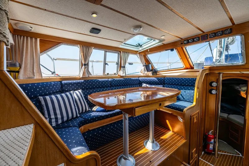 Slide: The Image of Nauticat 35 Pilot House 2000 interior with wooden table, blue seating, and large windows. - 22