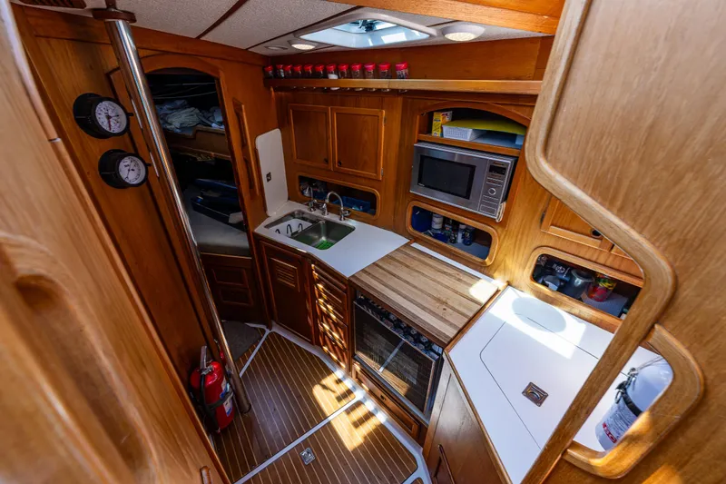 Slide: The Image of Nauticat 35 Pilot House 2000 interior with wooden cabinetry, kitchen appliances, and nautical decor. - 24