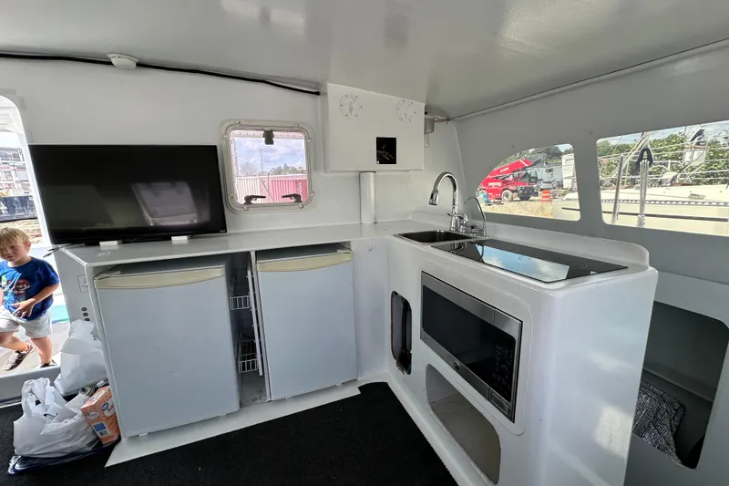 Slide: The Image of Interior of 2019 Kelsall 38ma catamaran with kitchen appliances and a child in the background. - 33