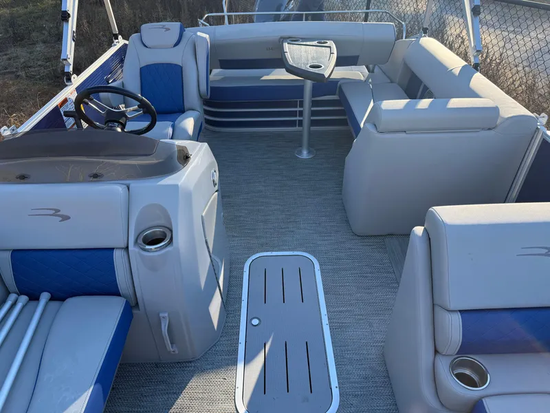 Slide: The Image of 2023 Bennington 21LSB pontoon boat covered, parked on a trailer under a clear blue sky. - 11