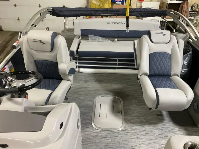 Slide: The Image of 2023 Bennington 23LTSB pontoon boat interior with seating and table, docked by the water. - 6