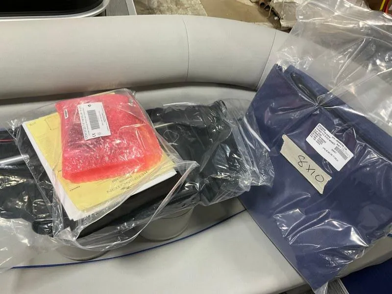 Slide: The Image of 2023 Bennington 208SL pontoon boat on trailer, parked near a marina under a cloudy sky. - 16