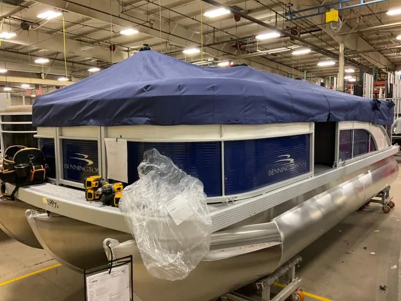 Slide: The Image of 2023 Bennington 208SL pontoon boat with spacious seating and canopy, docked by the shore. - 4