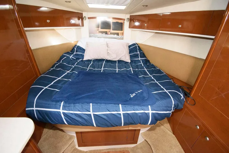 Slide: The Image of 2009 Sea Ray 330 Sundancer cabin with cozy bed, wooden cabinets, and nautical decor. - 17
