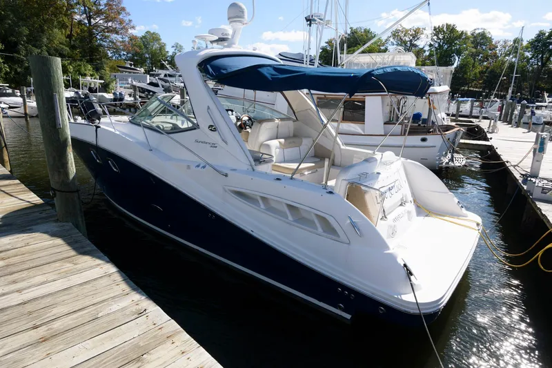 Slide: The Image of 2009 Sea Ray 330 Sundancer docked at marina, featuring sleek design and blue canopy. - 2
