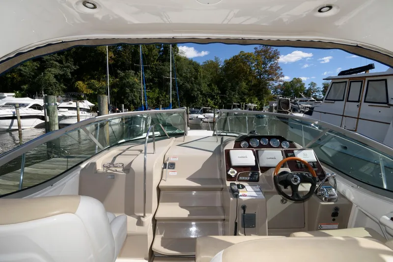 Slide: The Image of 2009 Sea Ray 330 Sundancer cockpit with steering wheel, gauges, and seating, docked at marina. - 5