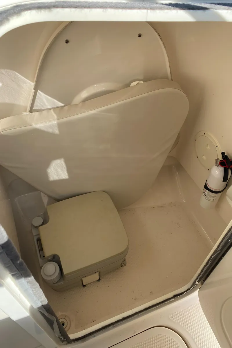Slide: The Image of 2013 Pursuit DC 235 Dual Console boat interior with portable toilet and fire extinguisher. - 11