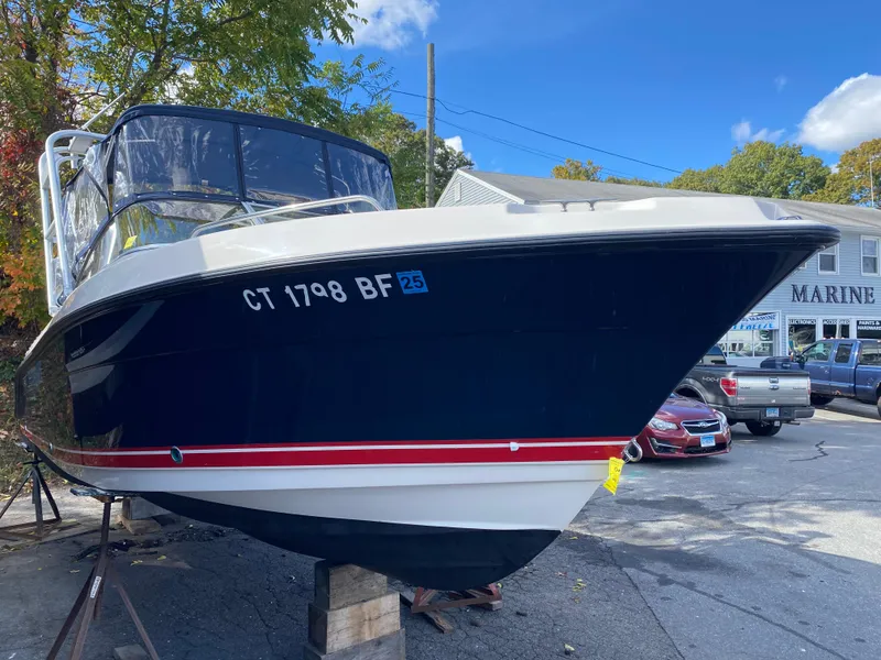 Slide: The Image of 2013 Pursuit DC 235 Dual Console boat on display in a marina parking lot. - 2