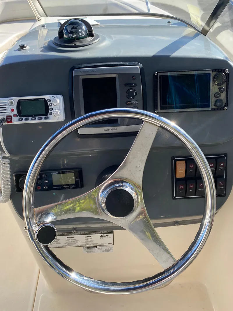 Slide: The Image of 2013 Pursuit DC 235 Dual Console dashboard with steering wheel and navigation instruments. - 4