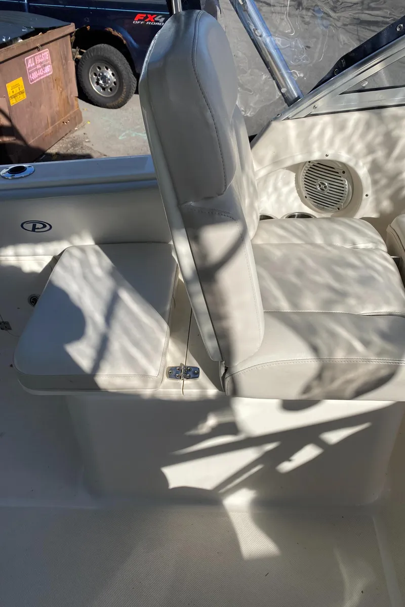 Slide: The Image of 2013 Pursuit DC 235 Dual Console boat interior with white seating and speaker. - 9
