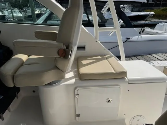 Slide: The Image of 2015 Pursuit OS 345 Offshore boat interior with beige seating and storage compartment. - 17