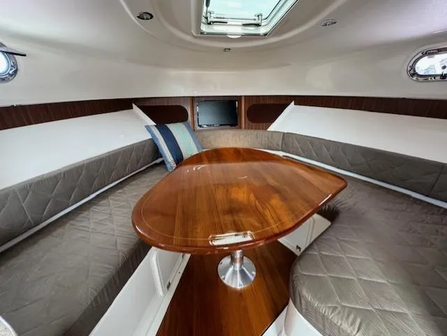 Slide: The Image of 2015 Pursuit OS 345 Offshore cabin with wood table and cushioned seating. - 19