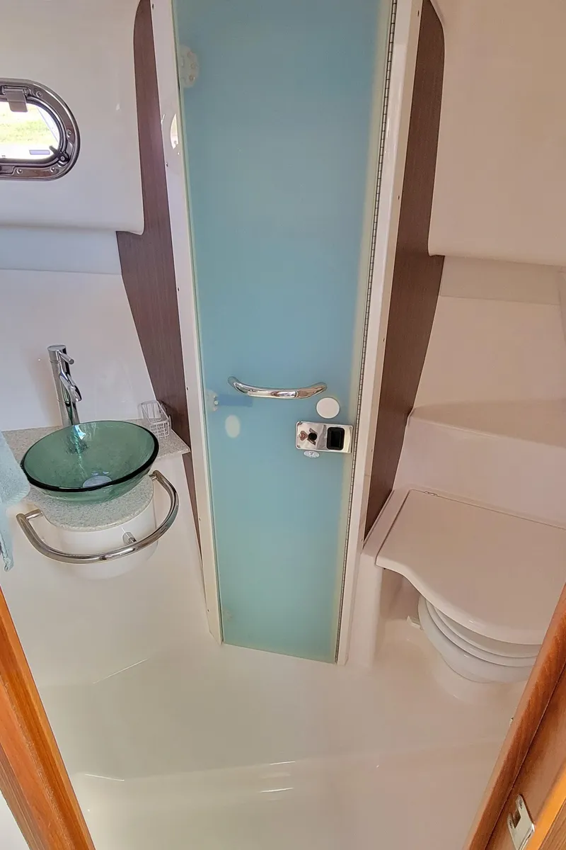 Slide: The Image of 2015 Pursuit OS 345 Offshore bathroom with modern glass sink and compact toilet. - 20