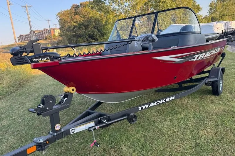 Slide: The Image of 2025 Tracker Pro Guide V-16 WT boat on trailer, red exterior, parked on grass. - 3