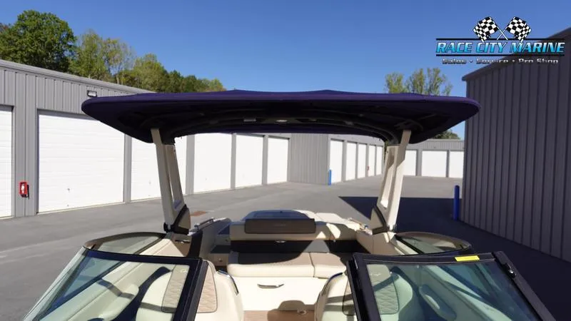 Slide: The Image of 2025 Chris-Craft Sportster boat with canopy, parked near storage units. - 45