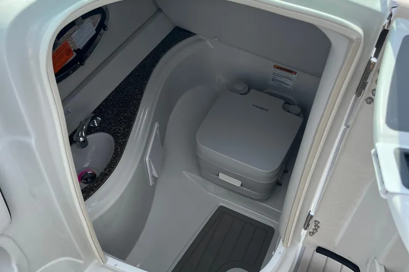 Slide: The Image of 2025 Crownline Eclipse E235 boat interior with compact marine toilet and sink. - 12